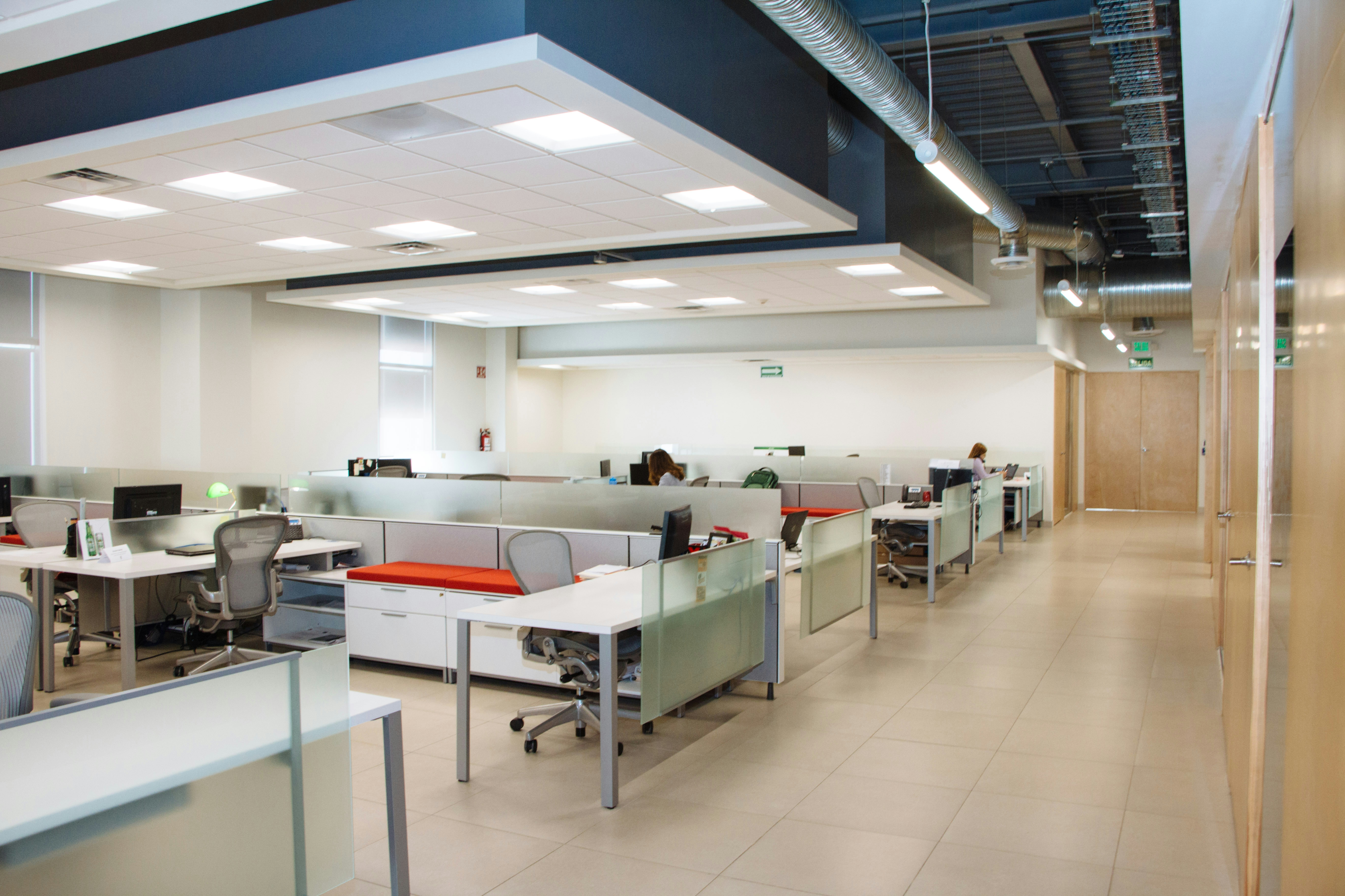 open plan office with rows of white desks and overhead LED panel lighting